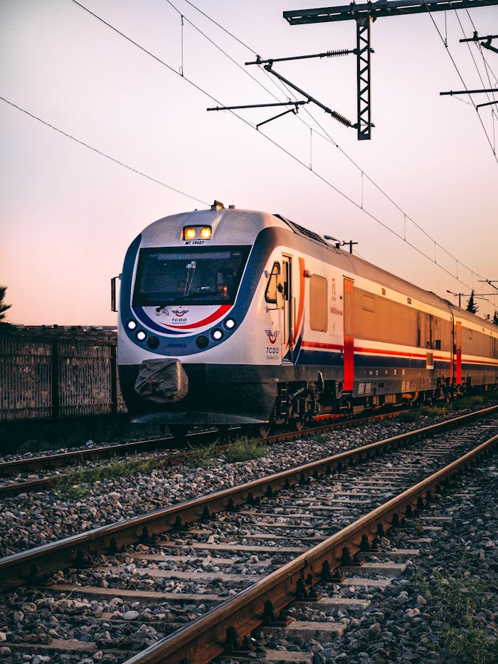 who-we-are Stylish passenger train traveling on railway tracks during a picturesque sunset.